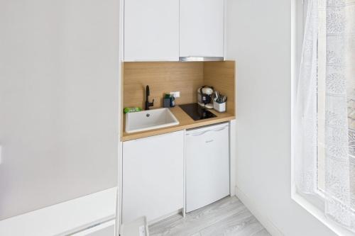 une petite cuisine avec des armoires blanches et un évier dans l'établissement Bleu saphir, à Troyes