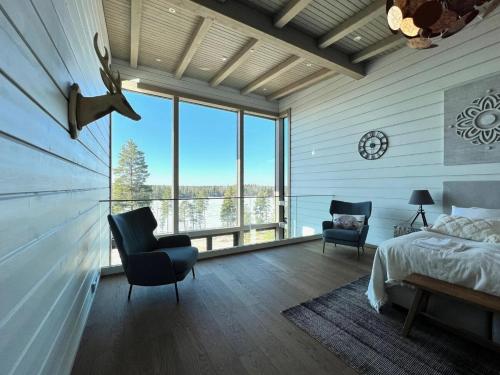 a bedroom with a bed and chairs and a large window at Naava Chalet Loft - Kaksikerroksinen lasiseinähuoneisto järvinäköalalla in Ähtäri