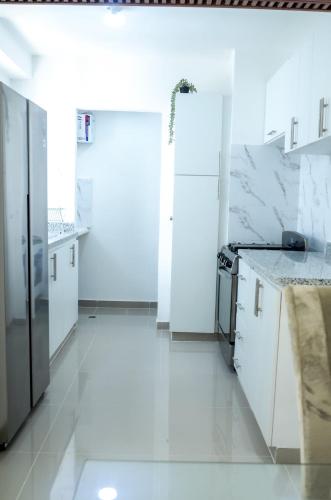 a white kitchen with white appliances and a white floor at Apartamento amplio con piscina 