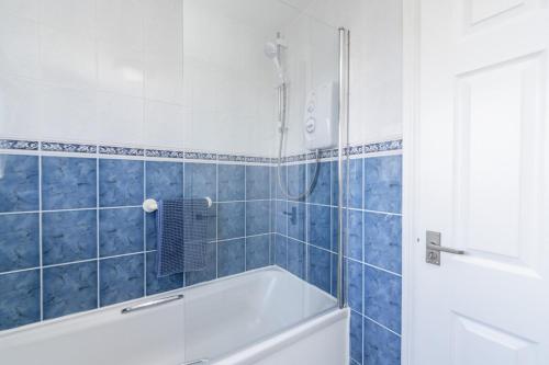 a blue tiled bathroom with a tub and a shower at Boddam getaway - CMC Stays in Boddam