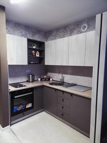 a kitchen with white and gray cabinets and a sink at Apartman Elite Stay Doboj in Doboj