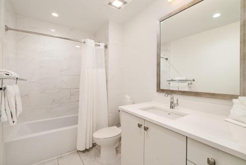 a white bathroom with a toilet and a sink at The Saddlery - Sound Check - 1 Block to Broadway in Nashville