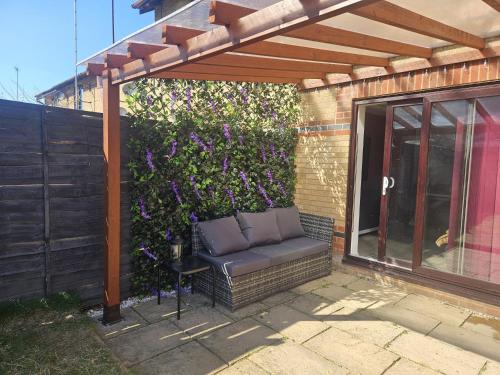 a pergola with a bench in front of a bush at Jasmin's House, 2 bedroom house, private Parking in Northampton