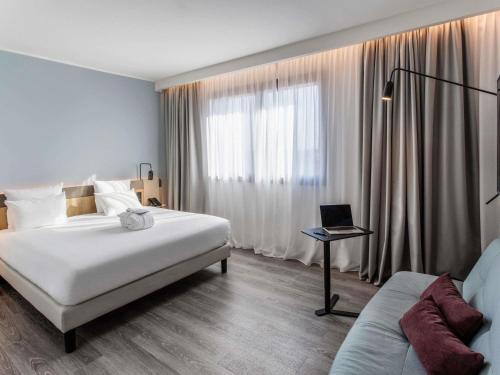 パルマにあるNovotel Parma Centroのベッド1台、ノートパソコン1台(テーブル上)が備わります。