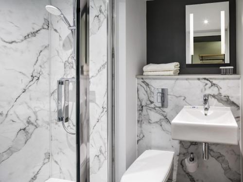 a white bathroom with a sink and a shower at ibis budget Swindon in Swindon