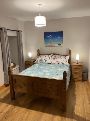 een slaapkamer met een houten bed en 2 nachtkastjes bij Belmullet Town Holiday Home in Belmullet