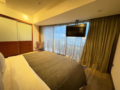 ein Hotelzimmer mit einem großen Bett und einem großen Fenster in der Unterkunft Alojamiento Céntrico En Sonata Lomas Angelopolis in Lomas de Angelopolis