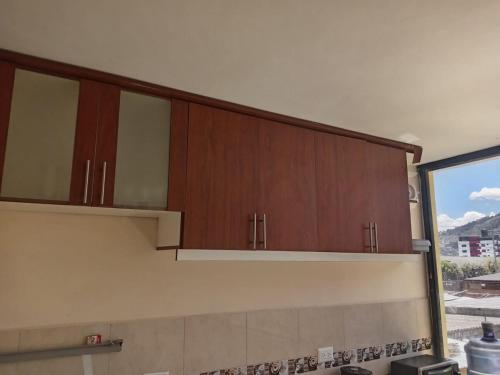a kitchen with wooden cabinets and a large window at Entire apartment in Ambato Ficoa in Ambato