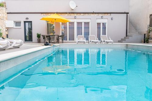 a swimming pool with a yellow umbrella and chairs at Haus Quadro in Rabac