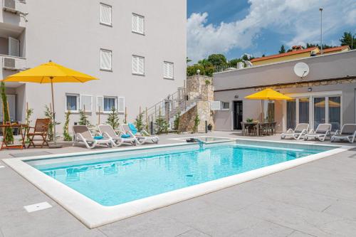 a swimming pool with chairs and umbrellas next to a building at Haus Quadro in Rabac
