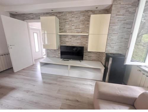 La Casa di Erika في Monasterolo del Castello: غرفة معيشة مع تلفزيون على جدار من الطوب
