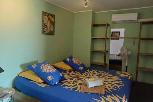 a bedroom with a blue bed with blue and yellow pillows at LA PERLE VERTE - Spacious studio near Papeete waterfront in Te Auae