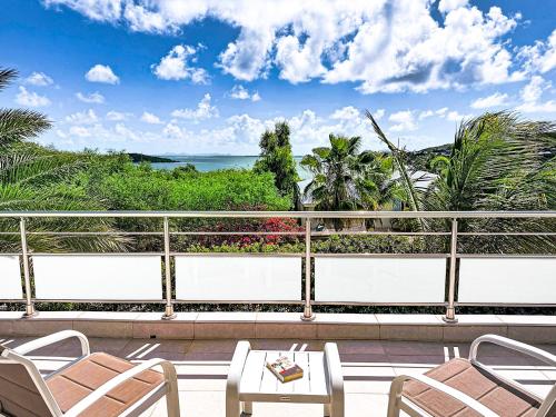 ein Balkon mit Stühlen und einem Tisch und das Meer in der Unterkunft Villa La Note Bleue in Cul de Sac