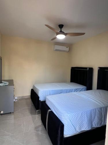two beds in a room with a ceiling fan at Mi refugio 2 in San Fernando de Monte Cristi