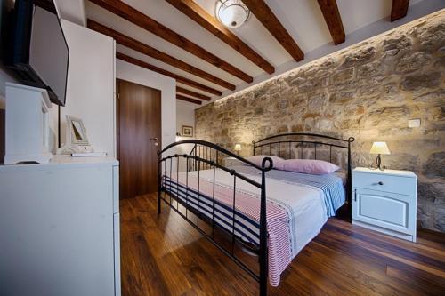 a bedroom with a bed and a stone wall at Riva Suite 1 in Komiža