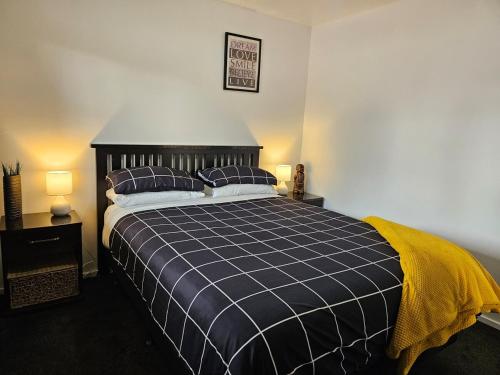 a bedroom with a blue and white bed with two pillows at Marg's on the Corner in Kumara