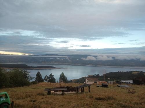 a picnic table in a field with a view of a lake at Zona de camping zoe in Guatavita