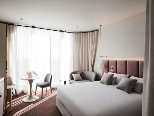 a bedroom with a large white bed and a table at Hotel Chadstone Melbourne MGallery Collection in Chadstone