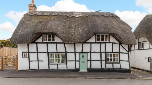 an old thatched cottage with a green door at Ramsbury Cottage in Ramsbury