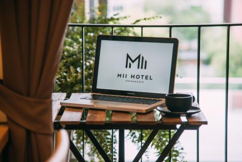 a laptop computer sitting on a table with a cup of coffee at Mii Hotel Srinakarin in Bangna