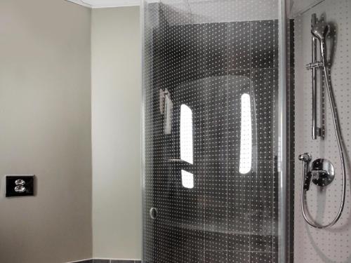 a shower with a glass door with a letter m on it at ibis Cahors in Cahors
