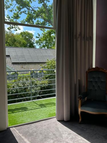 a room with a window with a chair looking out at a yard at Villa Vista in Wassenaar