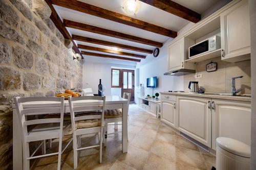 a kitchen with a table and a stone wall at Riva Suite 1 in Komiža