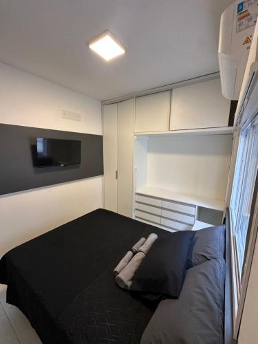 ein Schlafzimmer mit einem schwarzen Bett und einem TV in der Unterkunft Melhor apartamento de capão! 100m da praia in Capão da Canoa