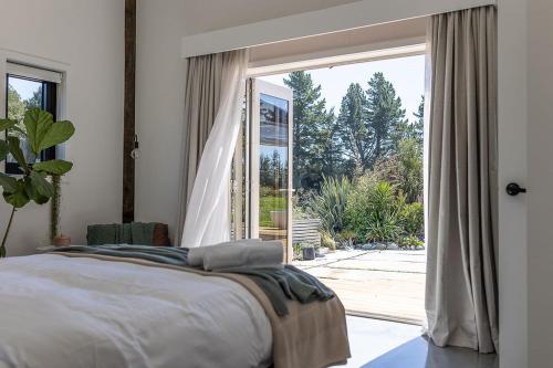 a bedroom with a bed and a large window at Halcyon Point in Hokitika Airport