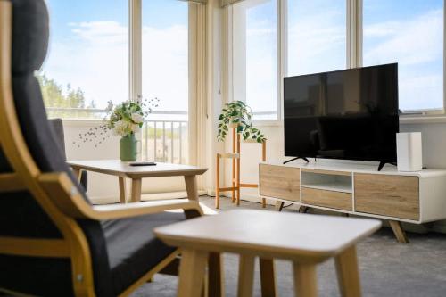 a living room with a flat screen tv and a chair at Brightly Renovated St Kilda Apt with Sea Views in Melbourne