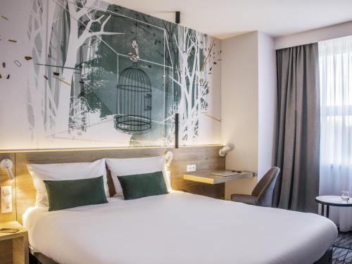 a hotel room with a bed and a bird cage painting on the wall at ibis Styles Kraków East in Krakow