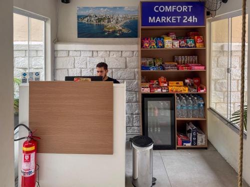a man sitting at a counter in a store at Barra Comfort Pousada in Salvador