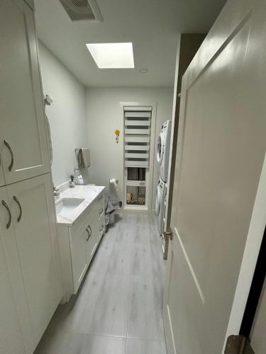 a white kitchen with a sink and a refrigerator at Skana South in Delta