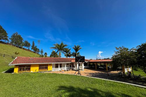 ein gelb-weißes Haus mit Palmen und einem Hügel in der Unterkunft Casa Finca Villa Laura 158 in Rionegro