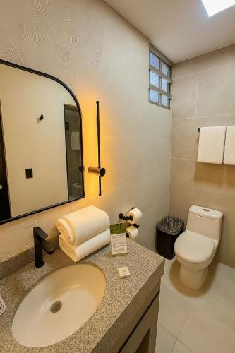 a bathroom with a sink and a toilet and a mirror at Hacienda Mazatlán sea view in Mazatlán