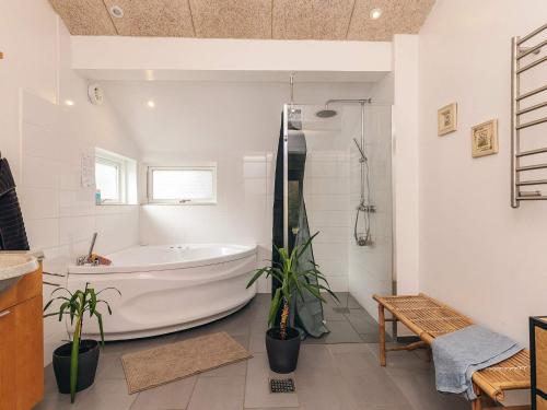 un baño blanco con bañera y plantas. en 4 star holiday home in Væggerløse, en Bøtø By