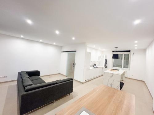 a living room with a black couch and a kitchen at Chambre Élégance et confort a Esch in Esch-sur-Alzette