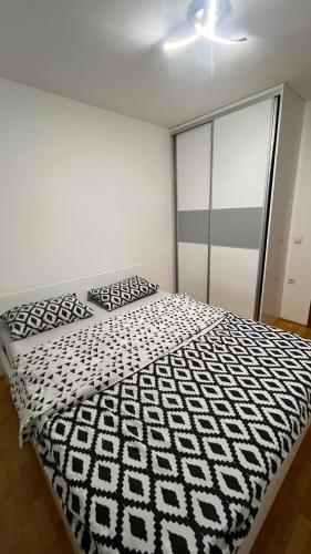 a bedroom with a bed with a black and white comforter at Stan na dan Šamac in Bosanski Šamac