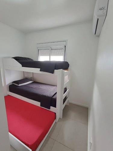 a room with two bunk beds with a red mattress at Apto 5 Estrelas no Centro de Pelotas in Pelotas