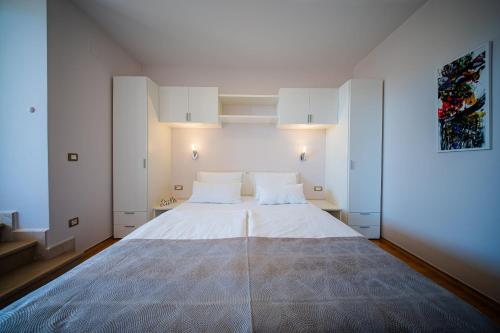 ein Schlafzimmer mit einem großen Bett mit weißen Wänden in der Unterkunft Apartments DYANA in Novalja