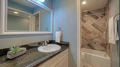 a bathroom with a sink and a mirror and a tub at 2 Pools Beach Boardwalk Access Studio Sleeps 5 Beach Bungalow by AvantStay in Port Aransas