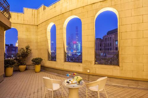 a building with a patio with a table and chairs at Jinjiang Metropolo Hotel Classiq,Shanghai Bund Circle in Shanghai