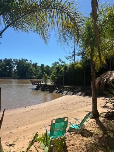 a green chair sitting on a beach near the water at PATO NEGRO in Tigre
