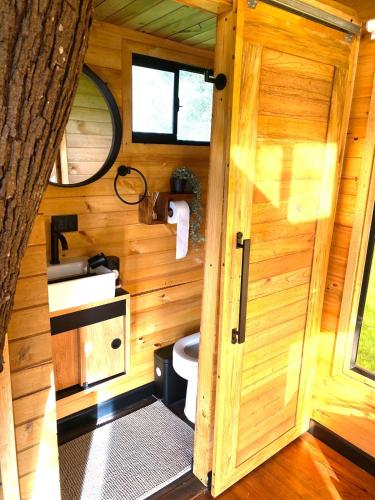 a wooden bathroom with a toilet and a door at Casa del Árbol Sesquile in Tres Esquinas