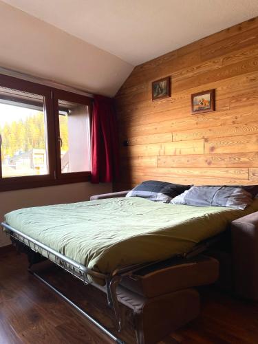 a bed in a room with a wooden wall at Ski&Sky Studiò 85 in Pila