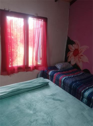 two beds in a room with a window at Casa Los colibrí in Frente Mar