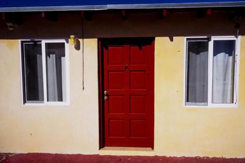 a red door on the side of a house at Rancho Percebu Beach Studio 6 in Don Pancho