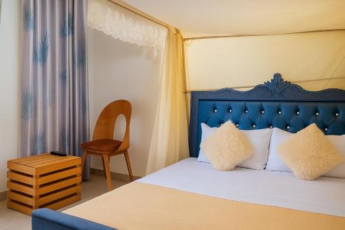 ein Schlafzimmer mit einem Bett mit blauem Kopfteil und einem Stuhl in der Unterkunft Noaz Hotel in Kampala
