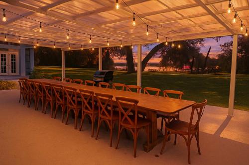 Una larga mesa de madera y sillas debajo de un pabellón. en Events & Weddings Welcome! Lake View Pool Home, en Dade City