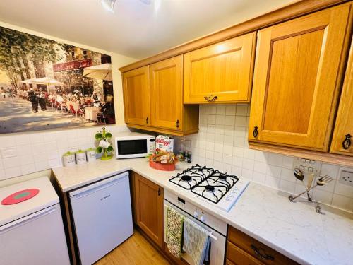 a kitchen with wooden cabinets and a stove top oven at Themed Cosy Home by Cannock Chase Forest in Rugeley